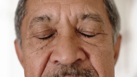 close up portrait of eyes of biracial senior man at home, slow motion