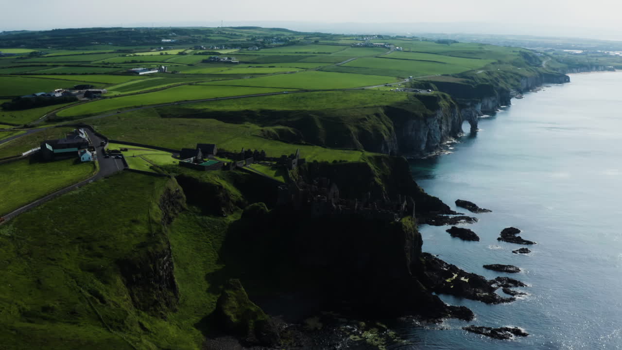 Aerial shot from afar of a coastline and the Dunluce Castle in Ireland