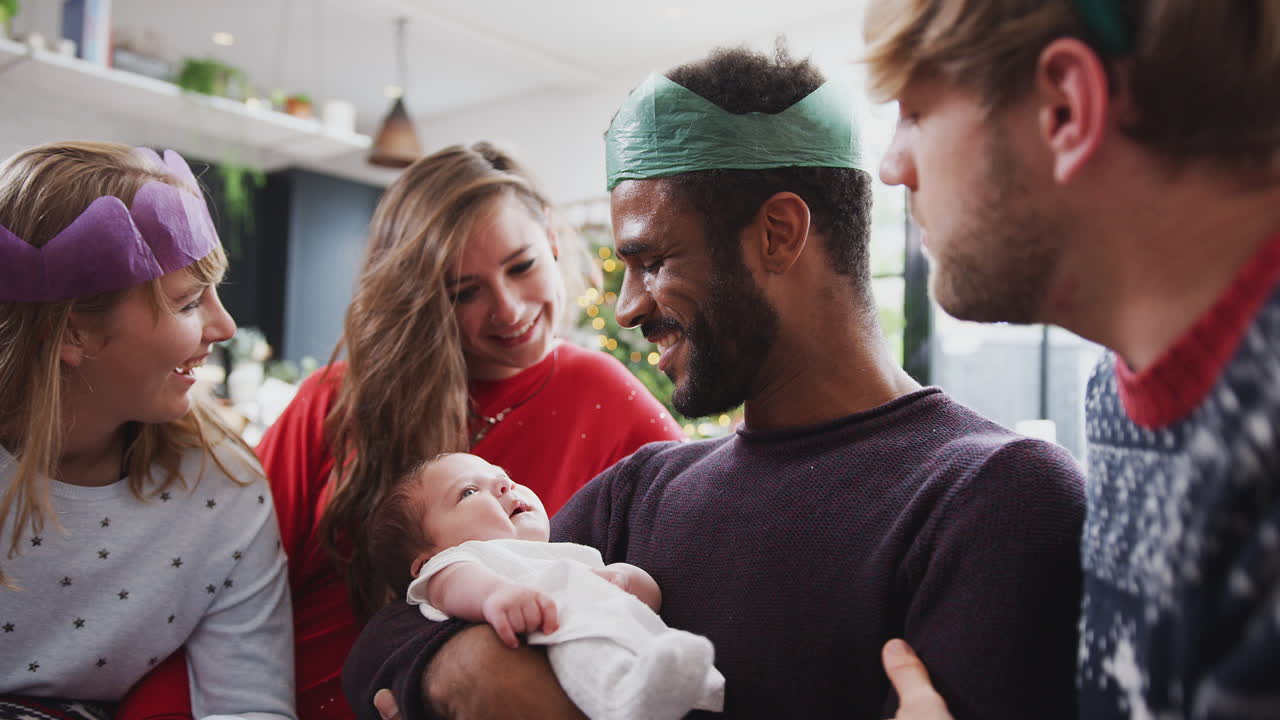 Schwules männliches Paar mit adoptierter Tochter, die das erste Weihnachten mit Freunden feiert