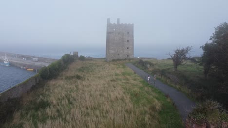 drone flying from the enterance of the keep to the castle with a drifting sea fog