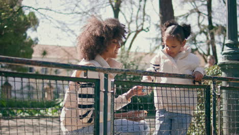 happy family feeding birds in sunny park. girl throwing crumbs