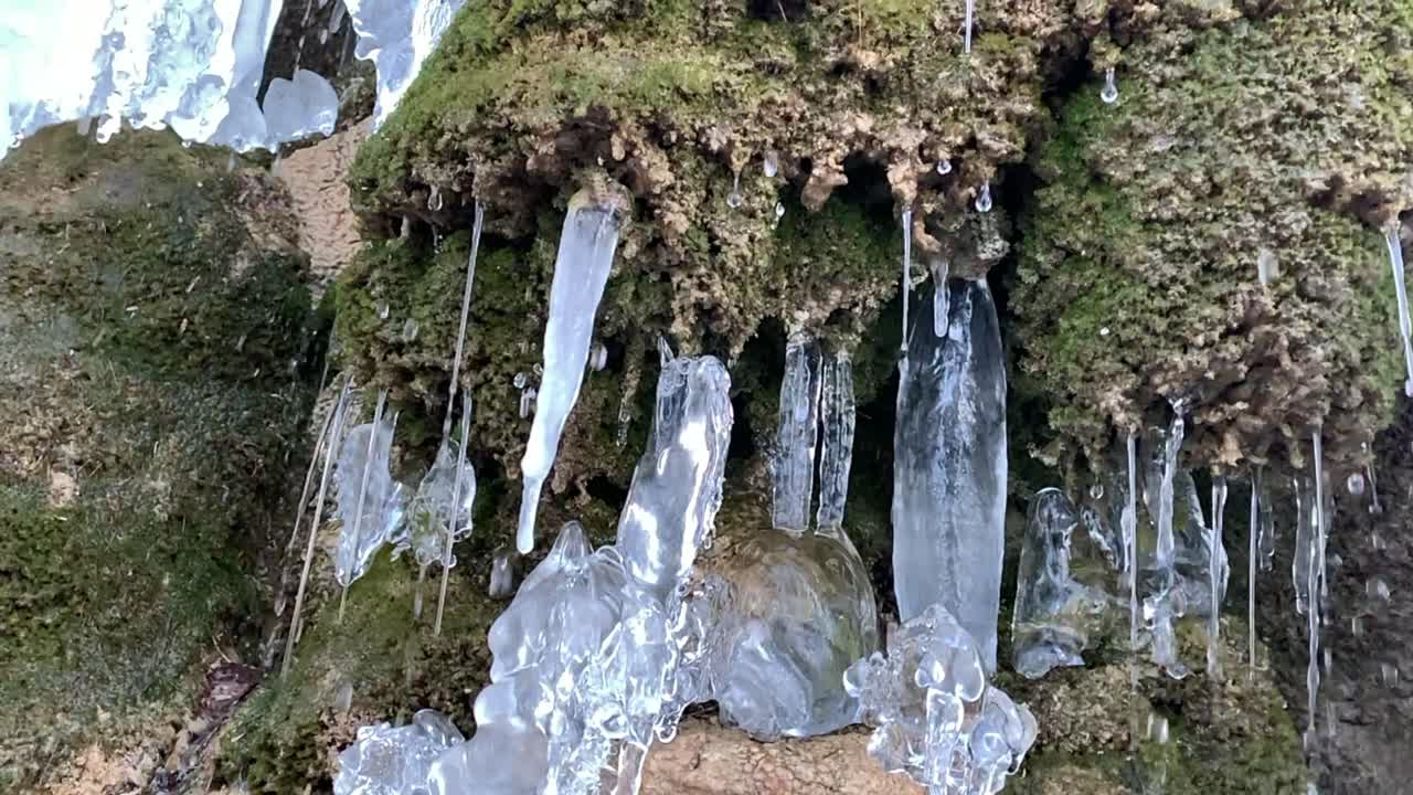 trozos de formación de carámbanos en un muro de piedra con corrientes de agua