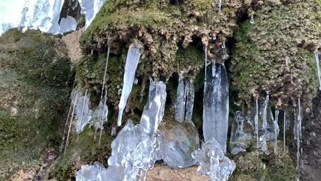 Chunks-of-icicle-formation-on-a-stone-wall-with-water-streams