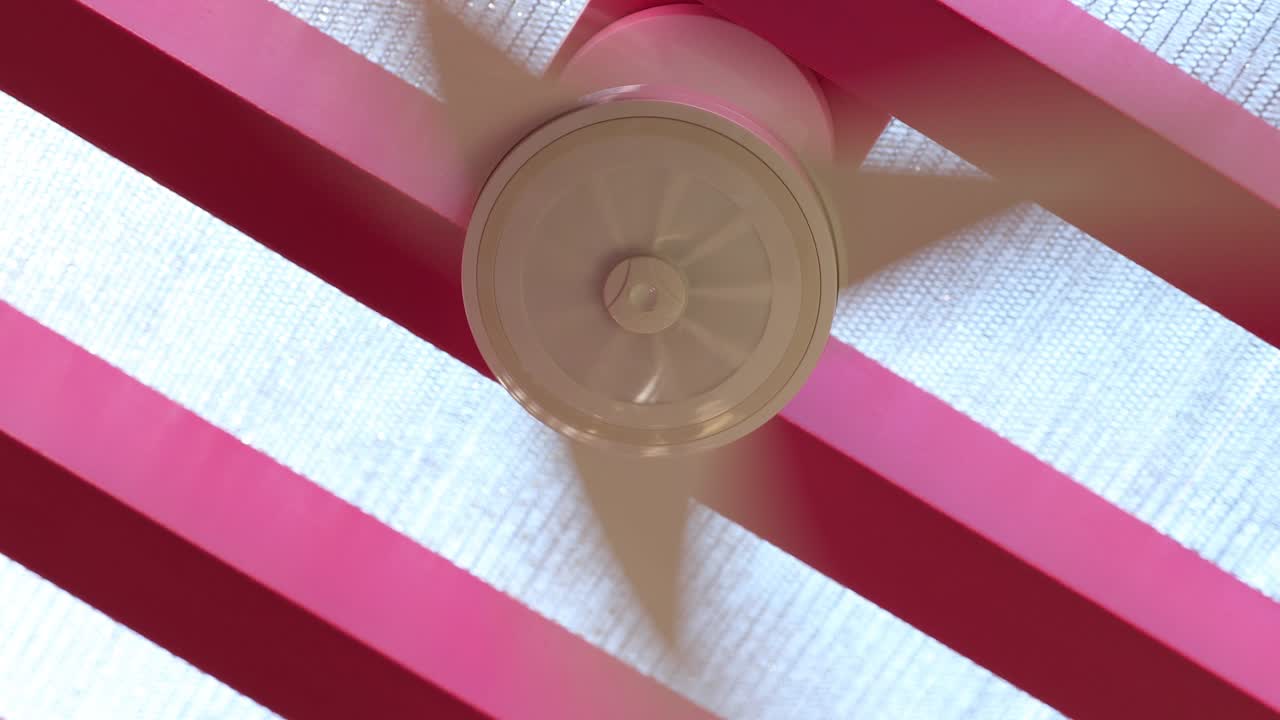 분홍색 배경으로 천장에서 공기를 방출하는 환기 팬