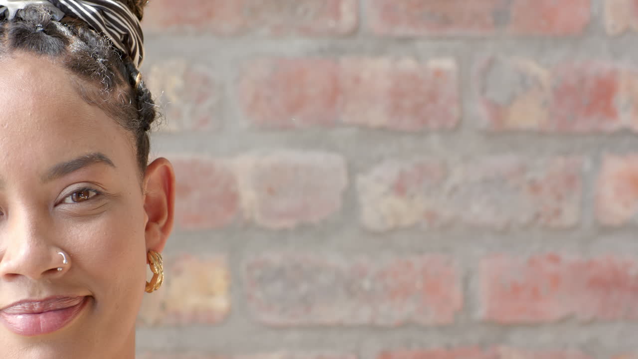 Confident woman with braided hair smiling against brick wall background, copy space
