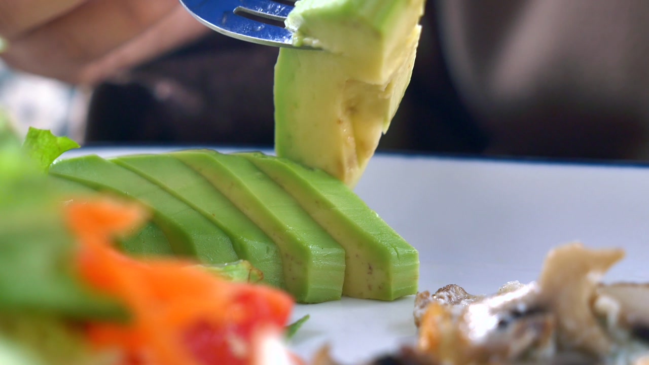 Close-up of a Fork Picking Up a Slice of Fresh Avocado