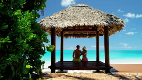 caucasian family sitting in a tiki beach hut