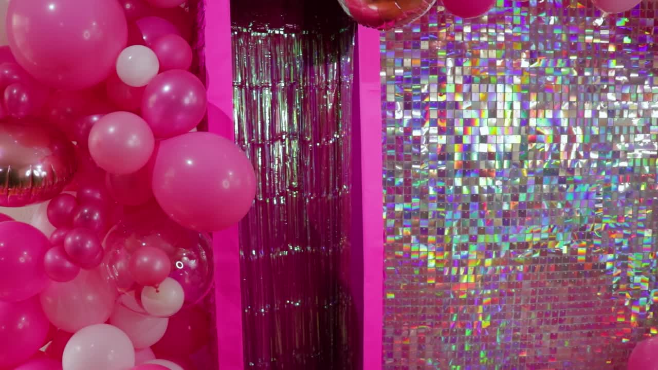 arreglo de globos rosados y blancos al lado de un telón de fondo de oropel brillante para la configuración de eventos festivos