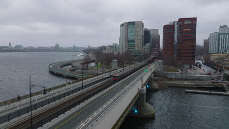 Two-subway-trains-passing-by-each-other-near-bridge-over-river.-Public-transportation-in-large-city.-Boston,-USA