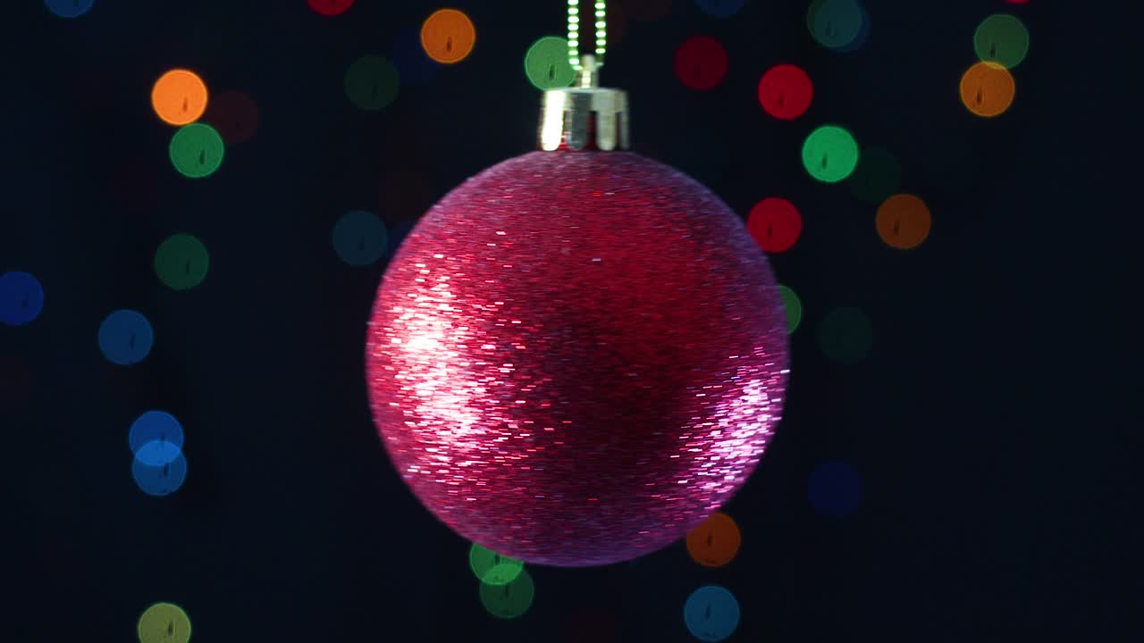 Enfeite de Natal vermelho com glitter balançando com luzes piscando ao fundo
