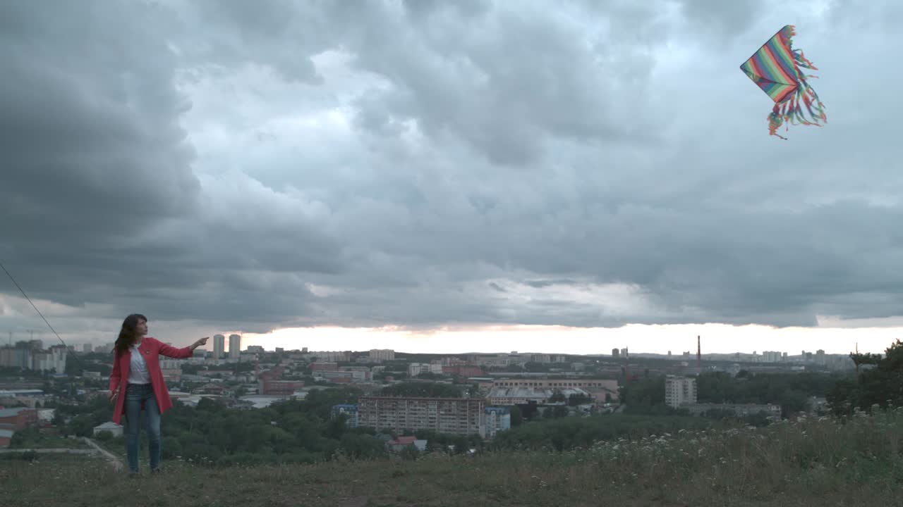 женщина летает на воздушном змее над городским пейзажем в облачный день