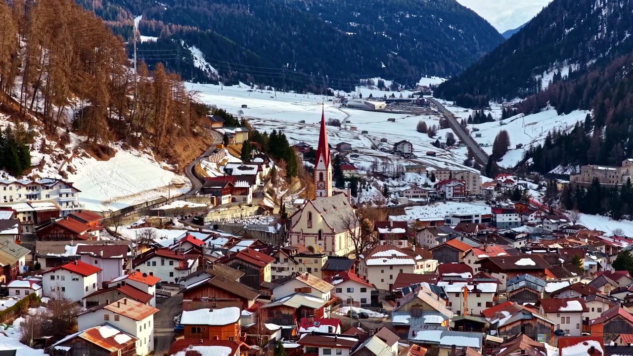 Cittadina austriaca di Nauders con campanile circondata da montagne e case innevate.