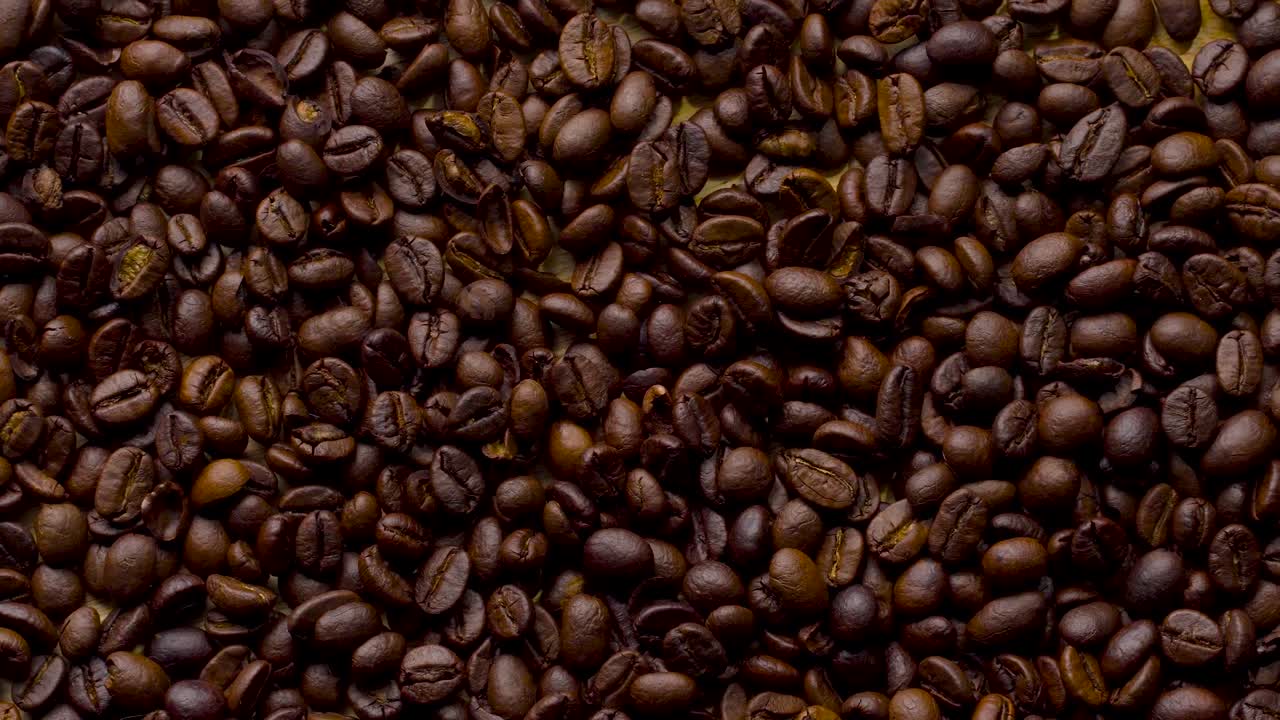 4K Footage. 4096x2304P.Fragrant coffee beans are roasted in a frying pan, smoke comes from coffee beans. The whole composition scrolls slowly around the camera. Scoop stir coffee beans.
