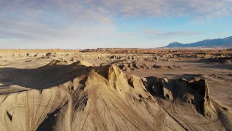 A-high-flying,-rotating-drone-shot-around-a-lone-motocross-rider-sitting-on-his-dirt-bike,-parked-on-top-of-a-tall-clay-formation,-looking-over-Caineville,-or-“Swing-Arm-City”-OHV-area-in-Utah