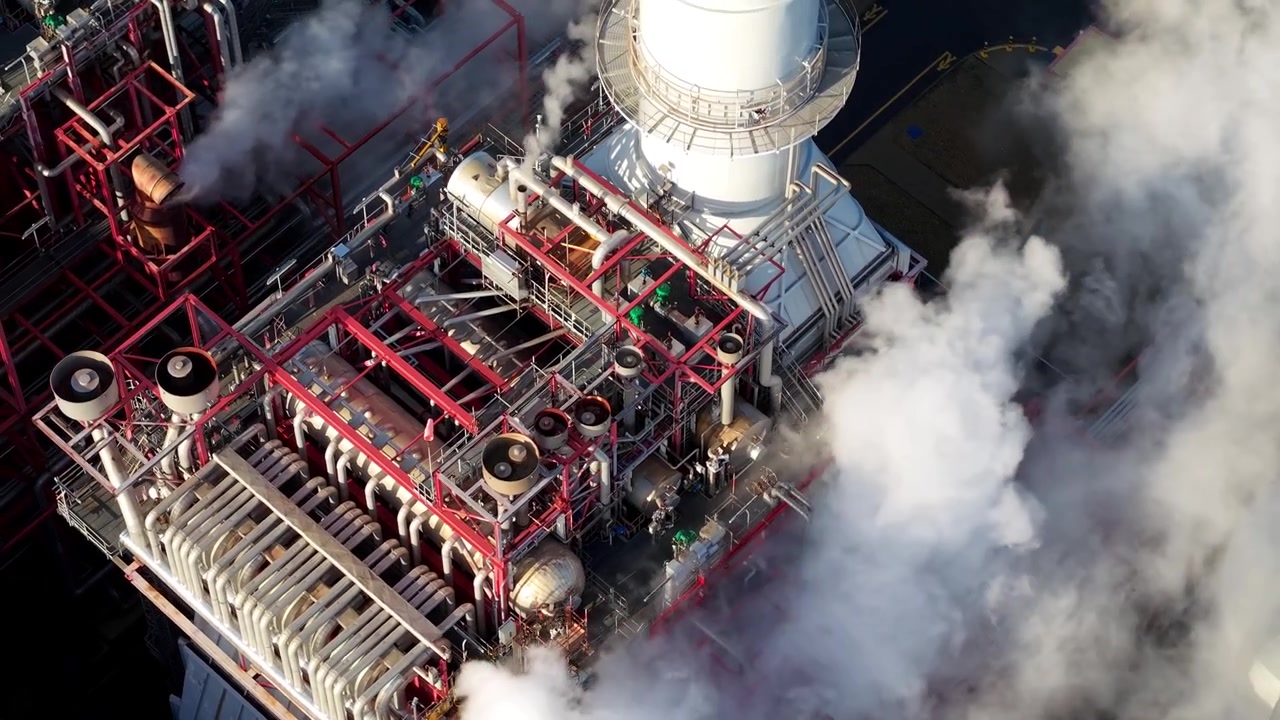 Ripresa aerea che si concentra sui tetti di edifici industriali in metallo, sulle canne fumarie e sulle strutture di tubazioni di servizio