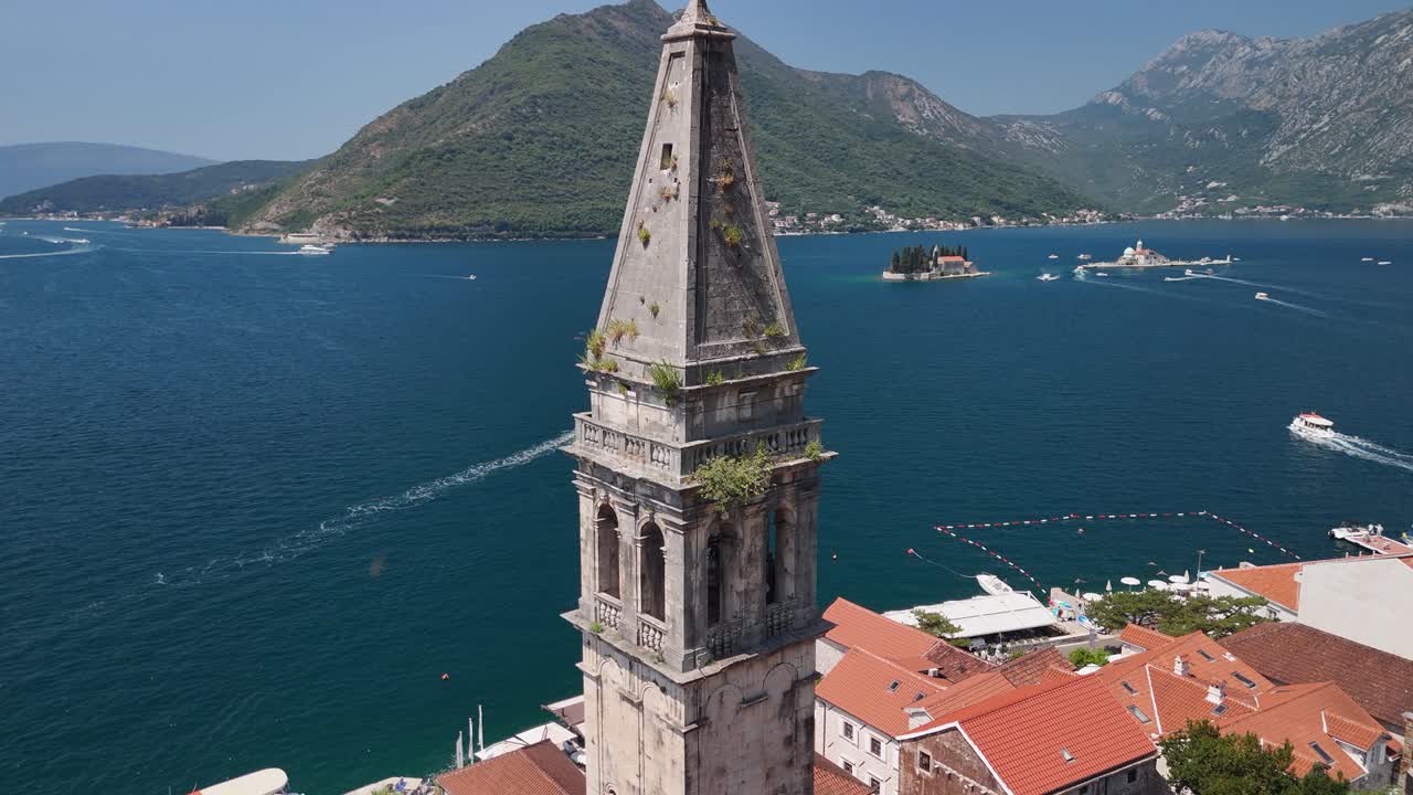 Aerial orbits church belltower in Perast, Our Lady of the Rocks beyond