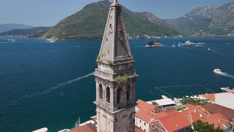 aerial orbits church belltower in perast, our lady of the rocks beyond