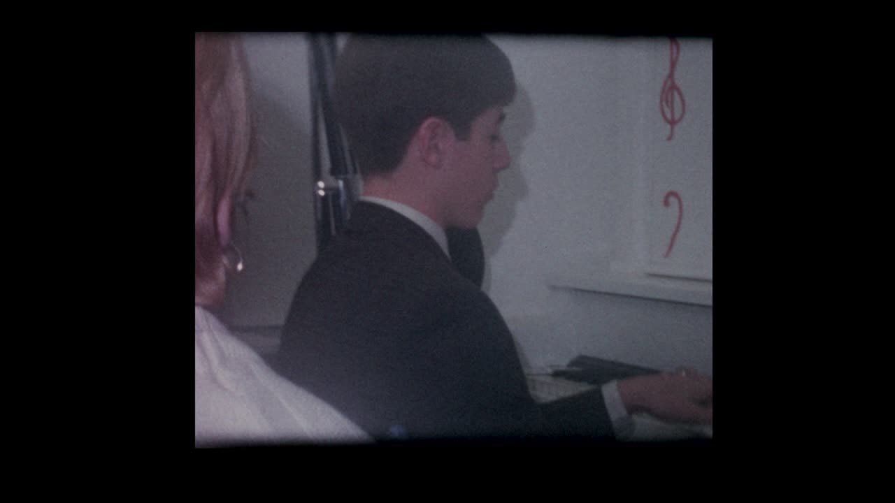 1967 niño toca un viejo piano vertical para sus amigos