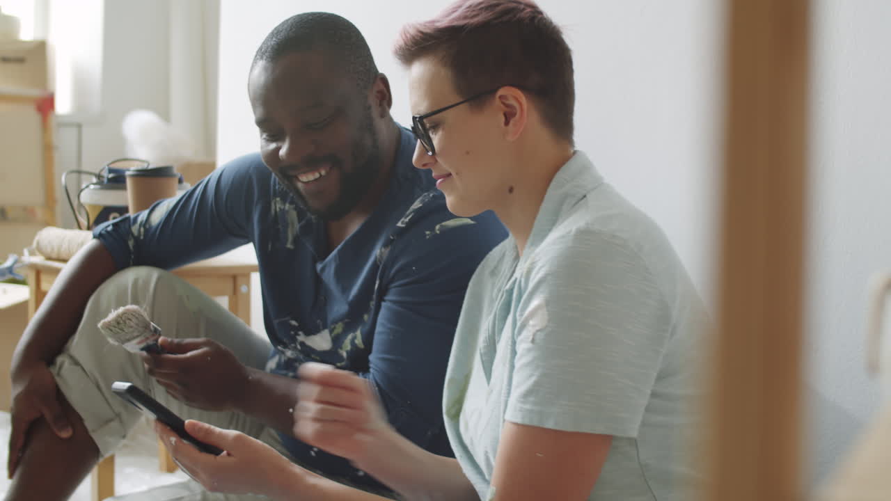집 리모델링 도중 스마트폰을 보는 부부