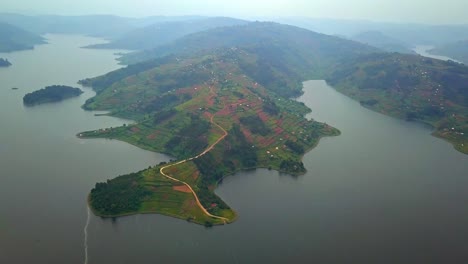 scenic drone shot shows lake bunyonyi’s peninsula surrounded by hills and patchwork farmlands, revealing the lake’s intricate shoreline and uganda’s lush highland terrain from above