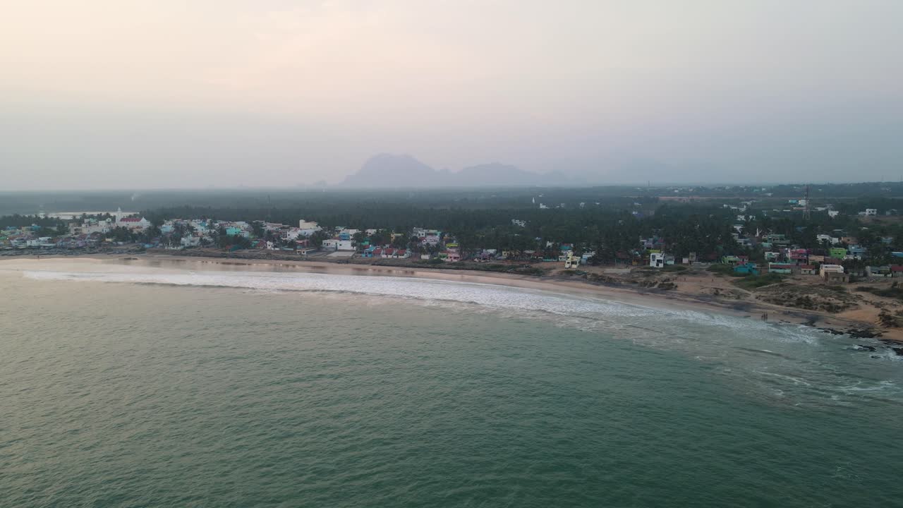 un dron aéreo filmado sobre kanyakumari capturando la fascinante mezcla de luces de la ciudad y olas del océano al anochecer.