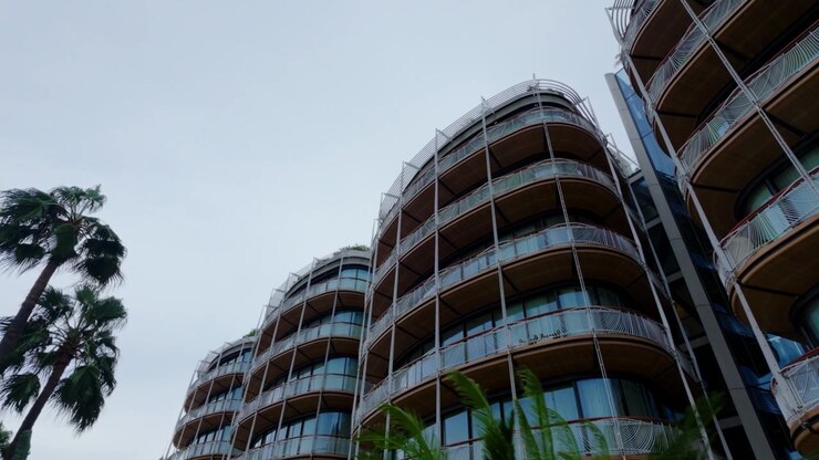 Moderno condominio a Monte Carlo, Monaco, con balconi in vetro curvo, palme, architettura di lusso della Riviera, Europa