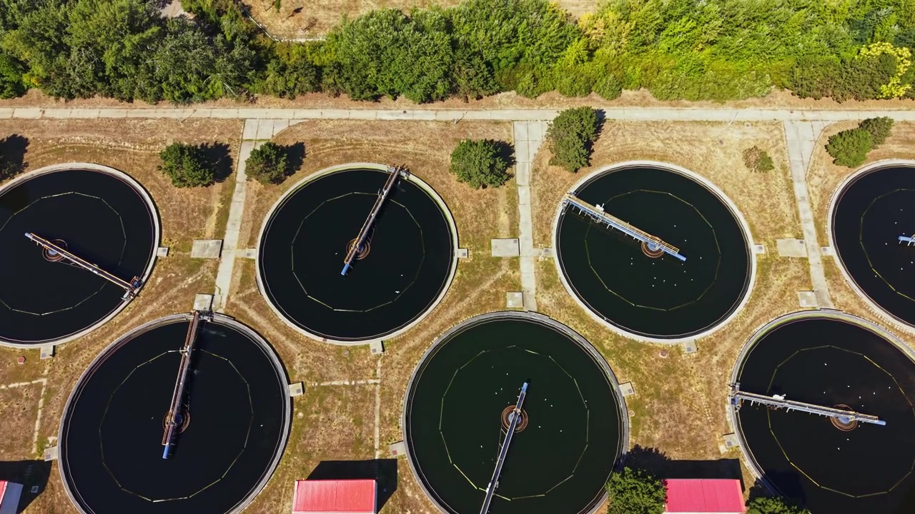 Water treatment facility shows multiple large circular tanks and machinery for processing water in an outdoor setting