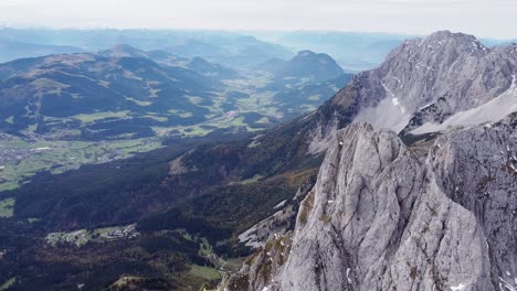 Aerial-of-steep-rocky-alpine-mountain-top-peaks,-epic-landscape-drone-scenery-view-into-valley