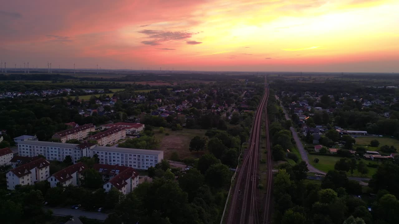 저녁에 작은 마을과 숲을 가로질러 철도에서 여행하는 여객 열차. 멋진 공중 전망 비행 회전 오른쪽 드론