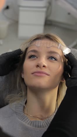 woman getting eyebrow measured for beauty treatment