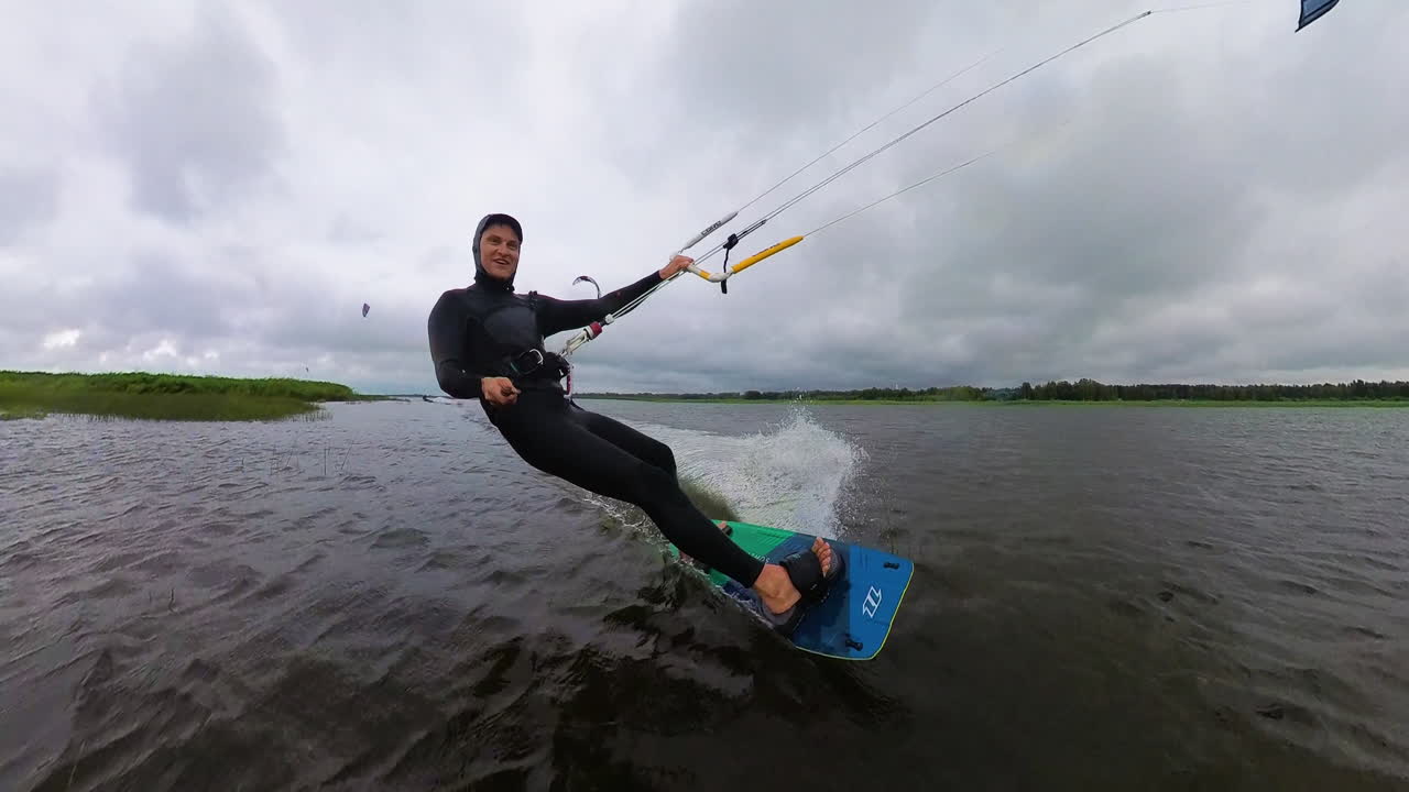 Man kiteboarding on flat water with twin tip board in Estonia on cloudy day.