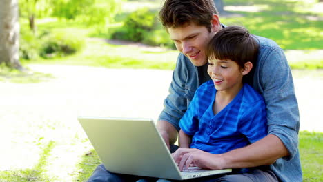 niño en la cintura de su padre usando una computadora portátil