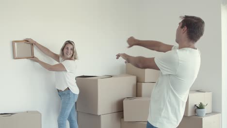 Married-couple-choosing-place-on-wall-for-picture-frame