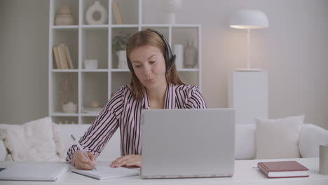 Junge-HR-Managerin-Führt-Vorstellungsgespräche-Per-Videochat-Auf-Einem-Laptop,-Vorstellungsgespräche-über-Das-Internet-Und-Macht-Sich-Notizen-In-Einem-Heft-Zur-Fernkommunikation