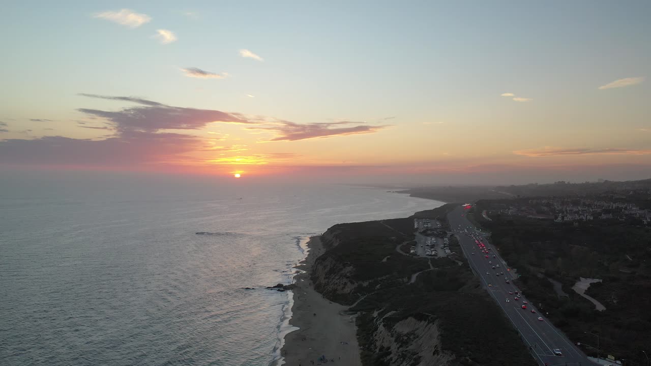 vista aérea 4k de una puesta de sol que ilumina impresionantes casas de lujo frente a la playa