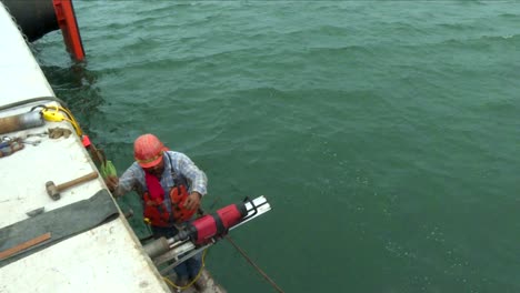 tilt down from the ocean to a man drilling floating on a platform