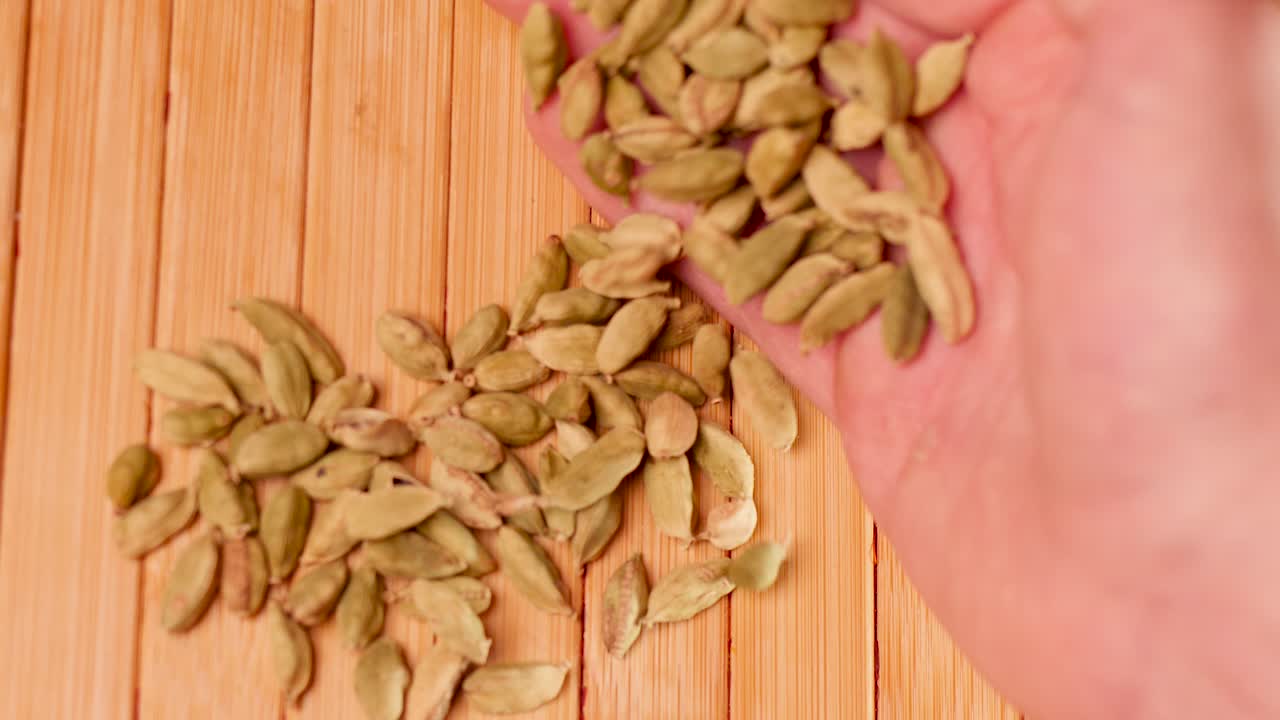 green cardamom pods being poured from hand