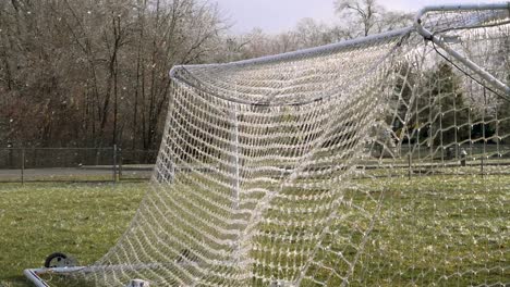 Cámara-Lenta:-Una-Pelota-De-Fútbol-Golpea-Una-Red-Helada-De-Una-Portería-De-Fútbol-Que-Explota-Hielo-Roto-En-El-Aire