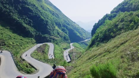 Dieses-Filmmaterial-Fängt-Die-Atemberaubende-Landschaft-Von-Ha-Giang-In-Nordvietnam-Ein-Und-Zeigt-Ein-Mädchen,-Das-Auf-Eine-Kurvenreiche-Straße-Blickt,-Die-Zwischen-üppigen-Grünen-Bergen-Eingebettet-Ist