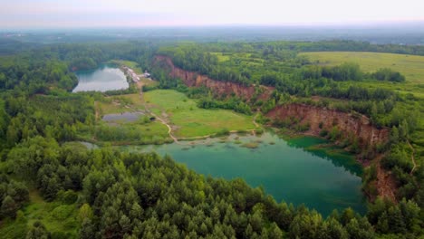 Drone-shot-of-Grodek-Park-wooden-footbridge-located-on-the-Wydra-Reservoir-with-lush-greenery-and-turquoise-water-in-Jaworzno,-Silesian-province