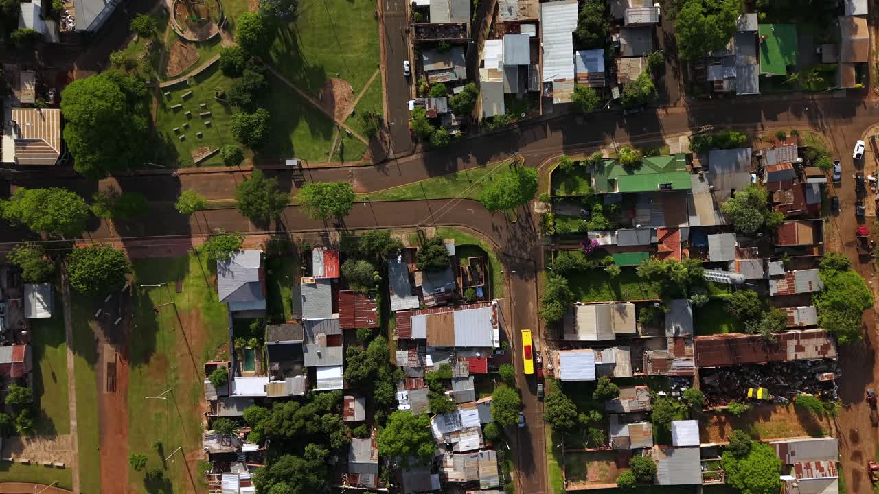 Aerial top-down view over a dense residential grid with small houses and patchwork roofs, intersecting streets, and green courtyards in Posadas, Misiones, Argentina
