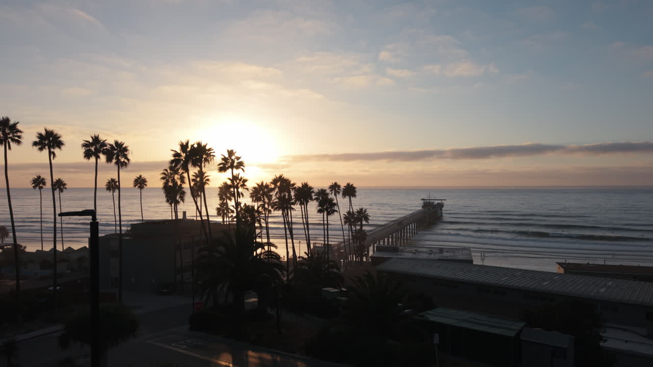 Ripresa aerea del Scripps Pier al tramonto a La Jolla, San Diego. La luce calda, le onde leggere e la costa del Pacifico creano una scena costiera rilassante, ideale per i viaggi, la natura, il turismo e i filmati della California.