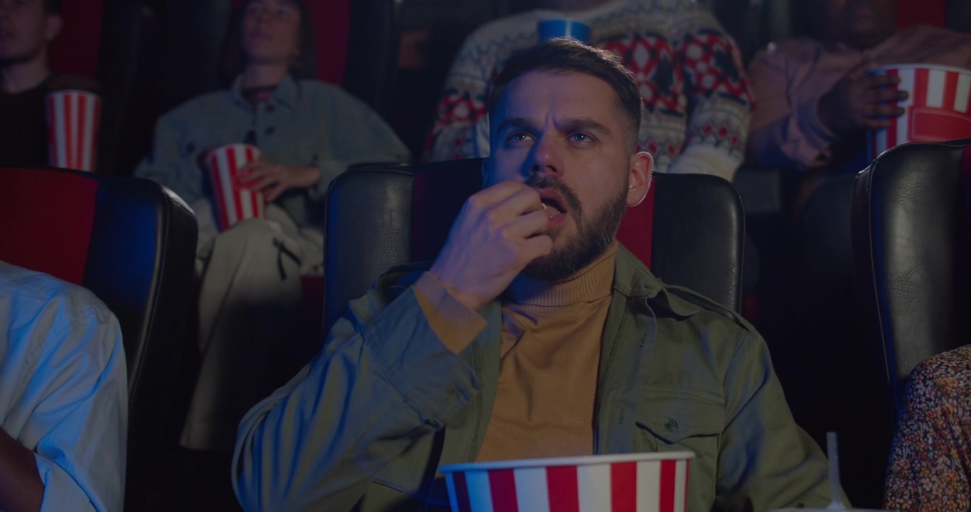 Giovane Uomo che Mangia Popcorn Guardando un Film al Cinema