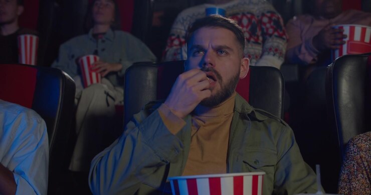Giovane Uomo che Mangia Popcorn Guardando un Film al Cinema