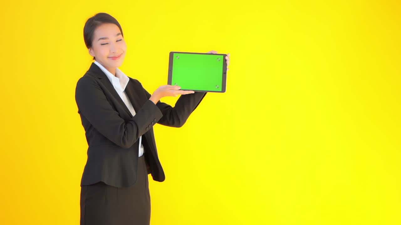 Asian model in business suit holding notebook electronic device with green screen. Chroma key ready demonstration, training, media, advertising concept. Copy space right