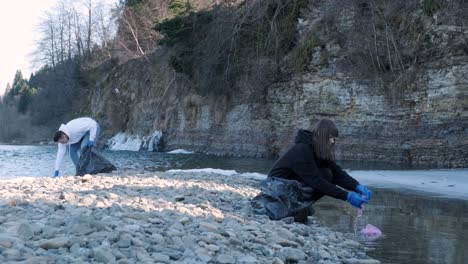 teamwork cleaning plastic on the beach. volunteers collect trash in a trash bag. plastic pollution and environmental problem concept. voluntary cleaning of nature from plastic. greening the planet