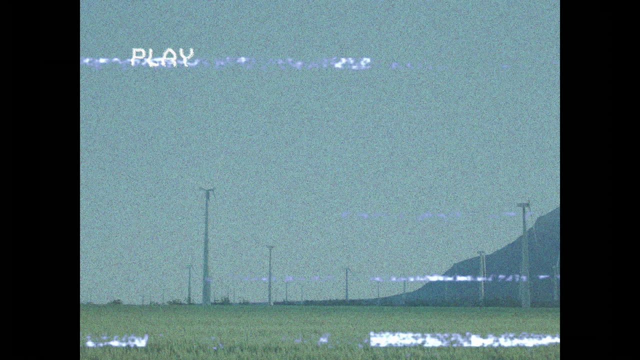 Animation of VHS-style static with PLAY text over landscape with distant hills
