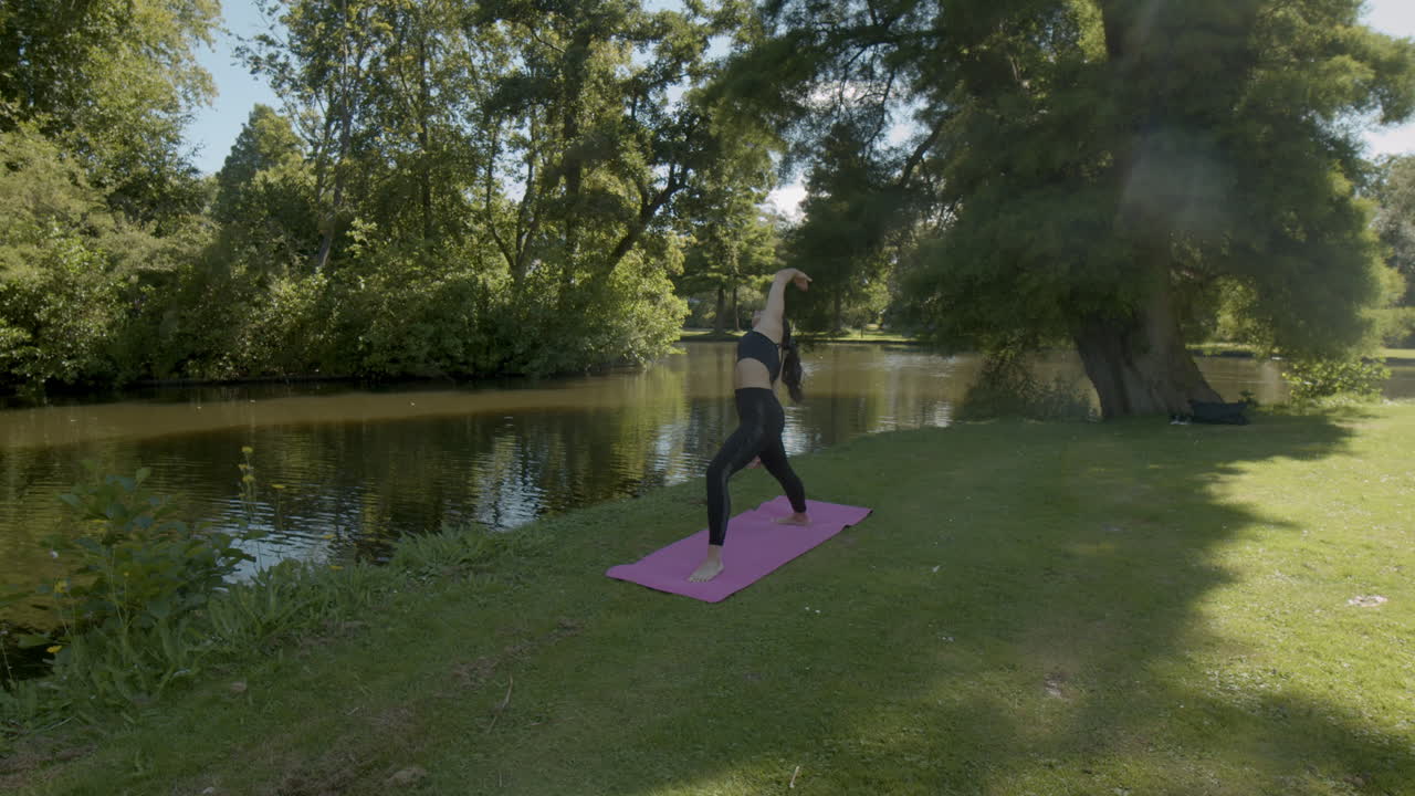 mujer haciendo una serie de ejercicios de yoga y terminándolos en un hermoso parque