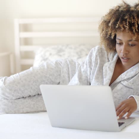 linda mujer usando una laptop en la cama