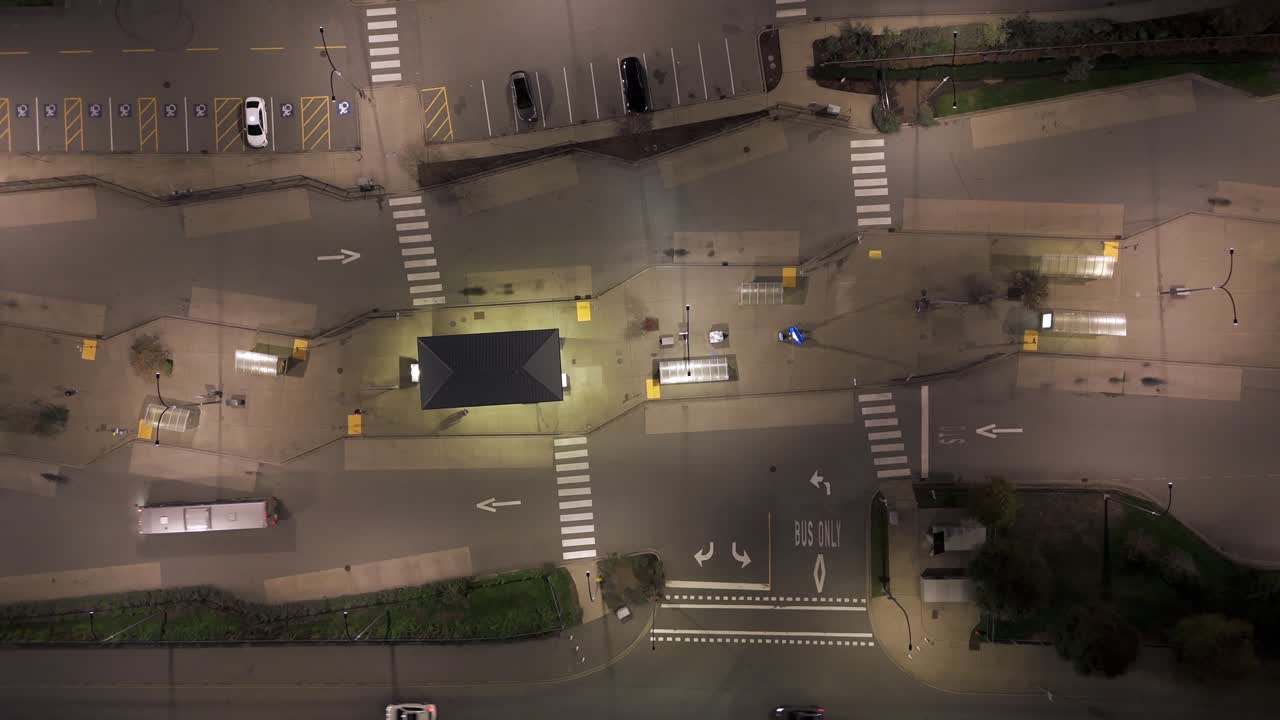 Vista cenital vertical aérea: un autobús y varios coches circulan por la calle de noche